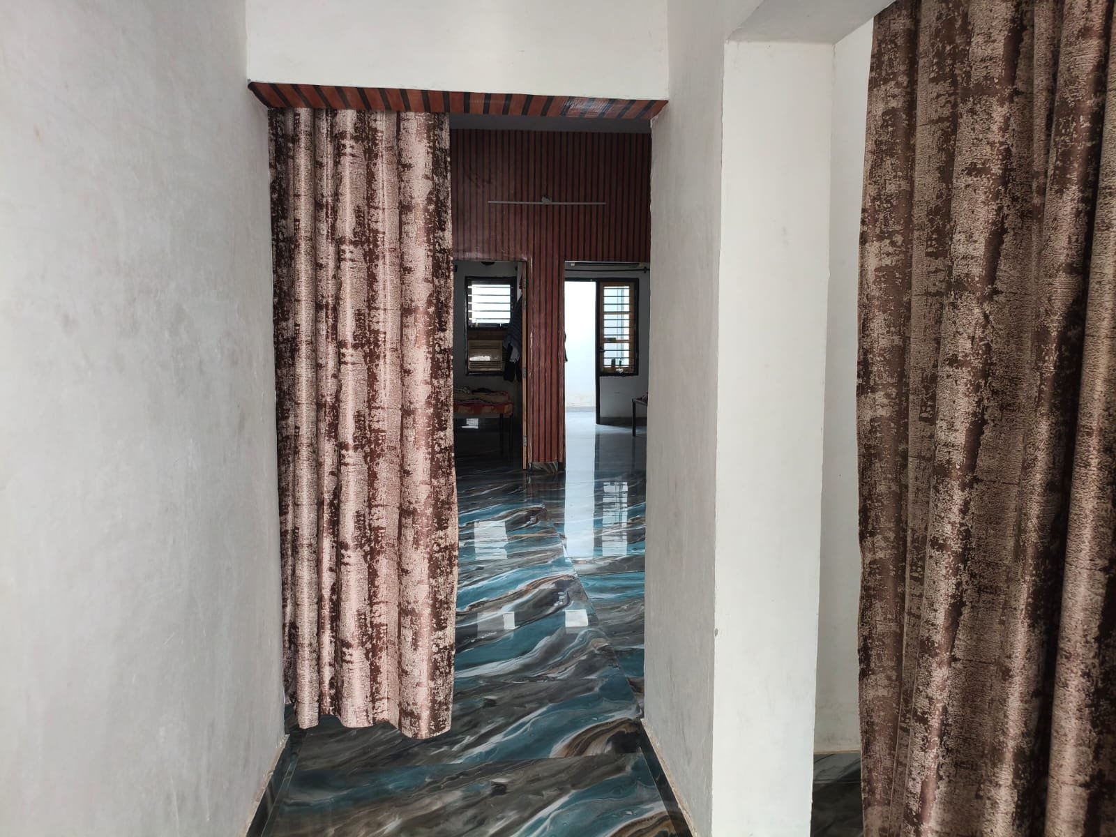 Interior passageway at Shibu Paying Guest in Khanna, with patterned curtains, bright windows, and polished flooring